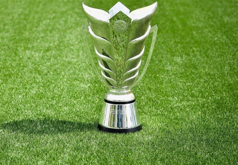 A silver trophy with leaf-like designs sits on a green artificial turf surface.