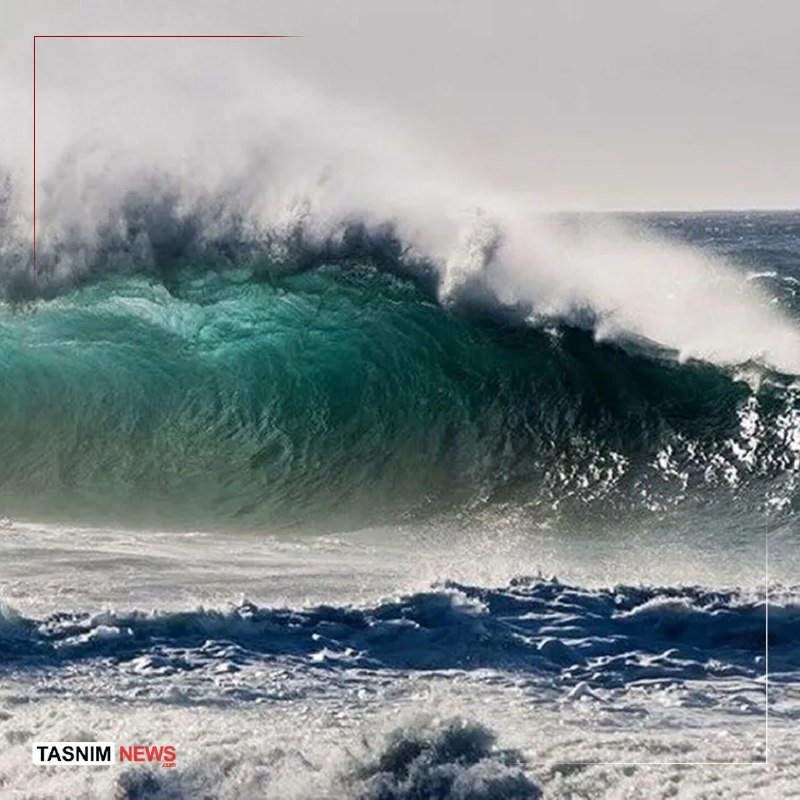 A large turquoise ocean wave crests and breaks, sending white spray into the air.