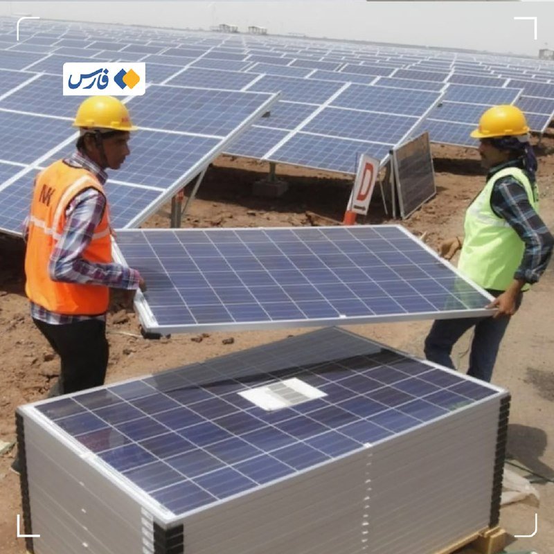 Two workers in hard hats and safety vests carry a solar panel at an outdoor solar panel installation site.