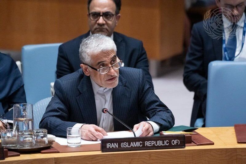 A gray-haired man in a suit speaks into a microphone at a desk labeled "IRAN (ISLAMIC REPUBLIC OF)," with other seated individuals visible behind him and a UN emblem in the corner.