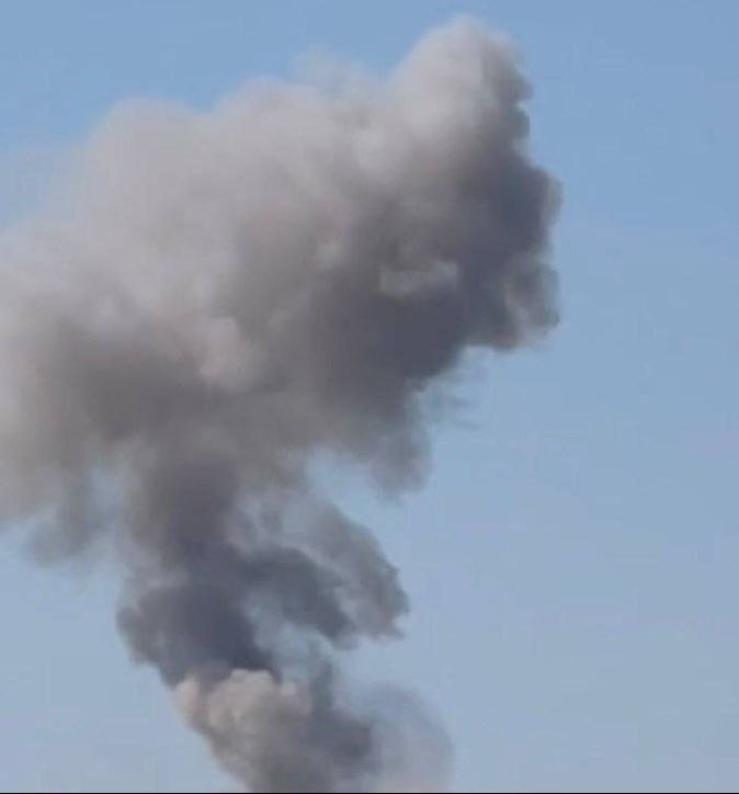 A large plume of gray and white smoke billows upward against a clear blue sky.