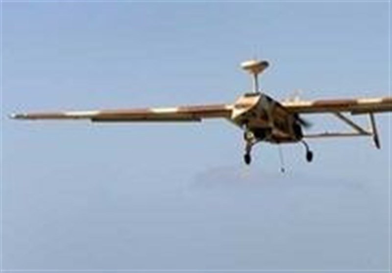A small, unmanned aircraft with extended wings and landing gear is shown in flight against a clear blue sky.