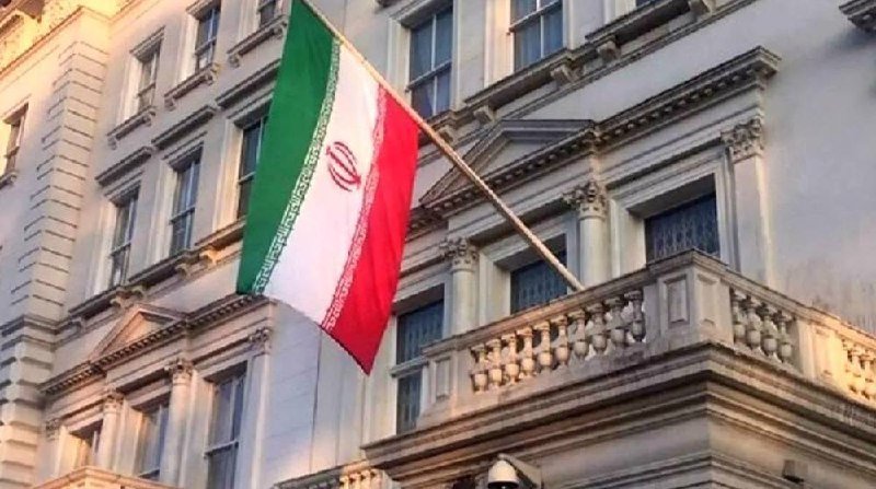 The Iranian flag flies from a stone building featuring ornate windows and a balustrade.