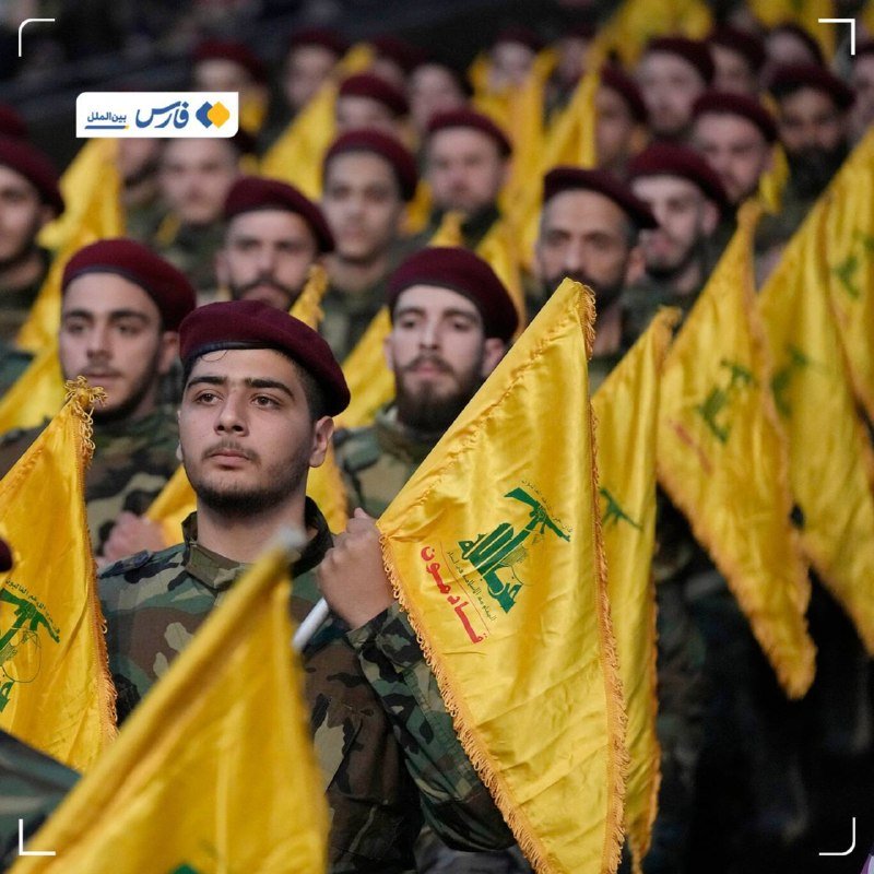 Rows of soldiers in camouflage uniforms and maroon berets stand at attention holding yellow flags bearing a green emblem.
