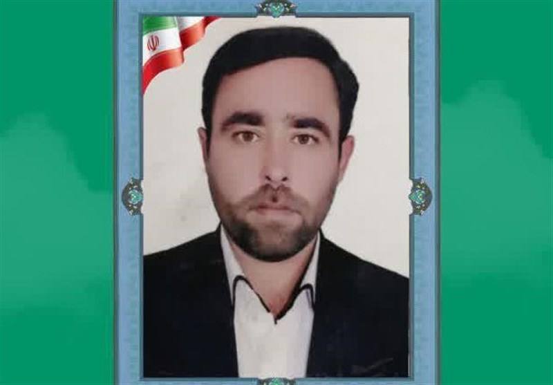 A framed portrait of a bearded man in a dark suit and white shirt, with an Iranian flag in the upper corner, set against a green background.