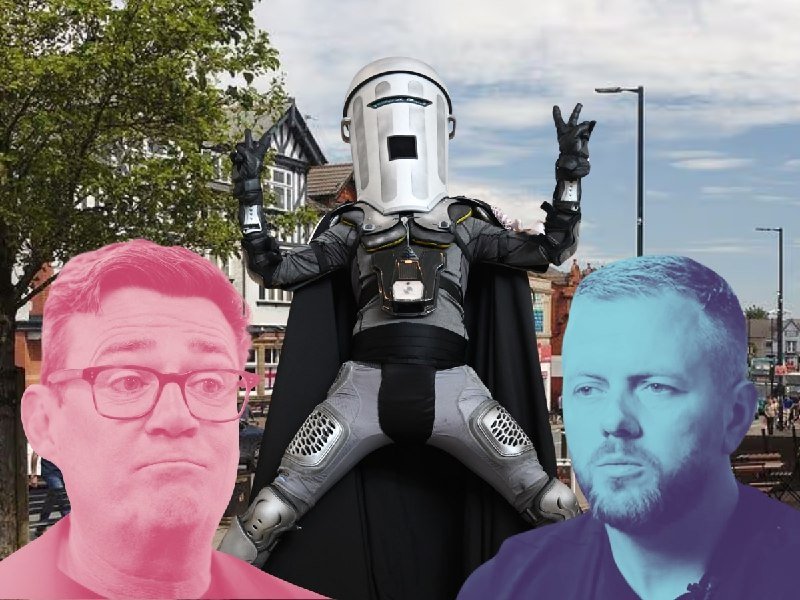 Two men's faces tinted pink and blue flank a central figure in a silver robotic helmet and black cape, standing on a street with trees and buildings behind.