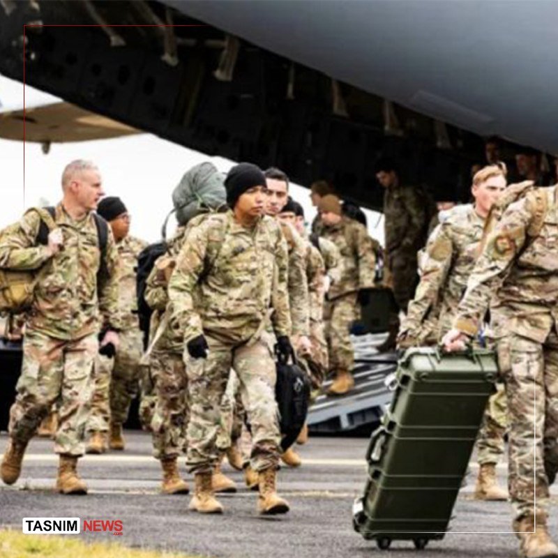 Soldiers in camouflage uniforms carrying duffel bags and a large green case walk away from a military aircraft on a tarmac.