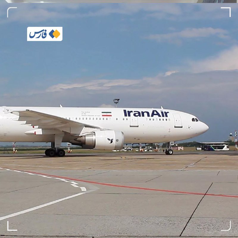 A white Iran Air passenger airplane is positioned on an airport tarmac, with an Iranian flag visible on its fuselage, under a partly cloudy sky.