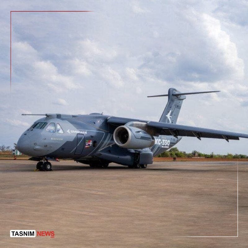 A gray Embraer KC-390 military transport aircraft sits on a paved runway under a cloudy sky, with "Tasnim News" watermark visible.