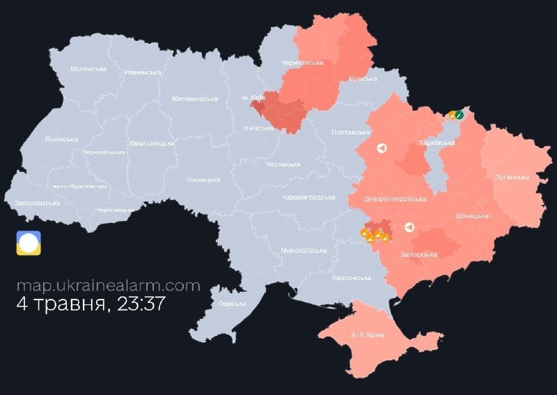A digital map of Ukraine displays regions shaded in gray and red, with several small icons indicating alerts, labeled "map.ukrainealarm.com" and dated "4 травня, 23:37."