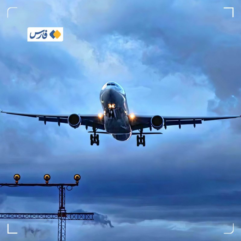 A large commercial airplane with illuminated headlights and deployed landing gear flies low against a cloudy twilight sky, approaching a runway marked by a lit approach lighting structure.