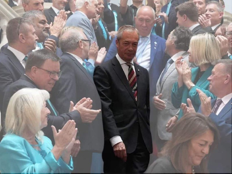 A man in a dark suit and striped tie walks through a crowd of formally dressed people who are clapping around him.