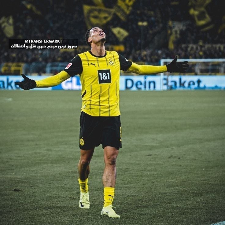A soccer player in a yellow and black Dortmund kit with "1&1" sponsorship stands on a pitch with arms outstretched and head tilted upward in celebration.
