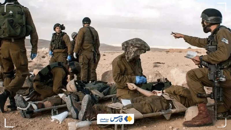 Soldiers in olive uniforms and helmets tend to wounded personnel on stretchers in a rocky desert landscape, with one holding a clipboard and another wearing a face covering.