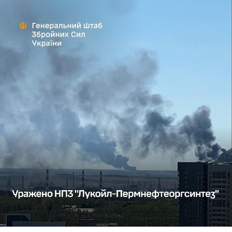Thick gray smoke rises from an industrial area with smokestacks, with a building in the foreground and Ukrainian text overlaid on the image.