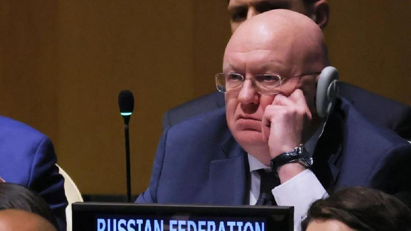 A bald man in a suit and glasses listens through a translation headset at a desk labeled "RUSSIAN FEDERATION."
