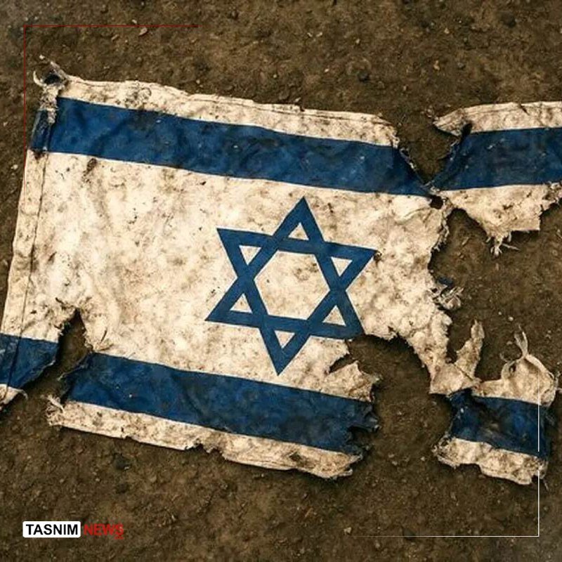 A torn, dirt-stained Israeli flag lies on muddy ground, with a "TASNIM NEWS" watermark visible in the corner.