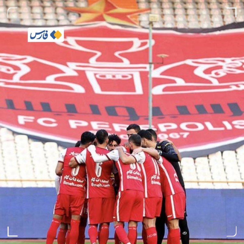 Soccer players in red and white uniforms huddle together on a field in front of a large FC Perspolis banner covering stadium seating.