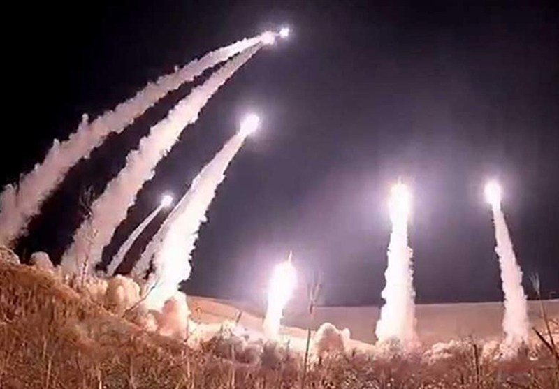 Multiple bright projectiles launch upward into a dark night sky, leaving thick white smoke trails above a snow-covered landscape.
