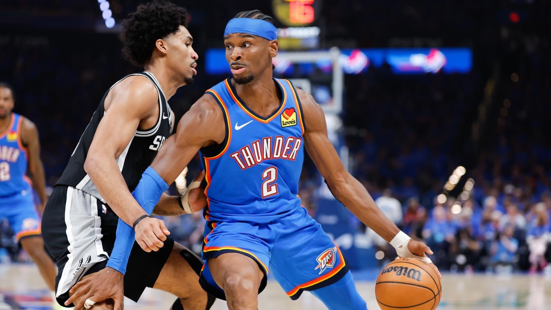 An Oklahoma City Thunder player wearing jersey number 2 dribbles the ball while being defended by a player in a black and white uniform during a basketball game.