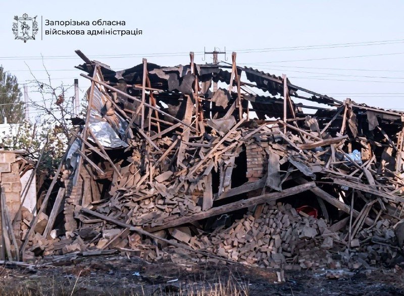 A collapsed brick building with shattered wooden beams and debris, featuring a logo and Cyrillic text reading "Запорізька обласна військова адміністрація" in the upper left corner.