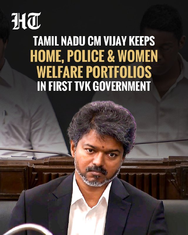 A news graphic featuring a bearded man in a black suit seated in a wooden assembly hall, with text overlay reading "TAMIL NADU CM VIJAY KEEPS HOME, POLICE & WOMEN WELFARE PORTFOLIOS IN FIRST TVK GOVERNMENT."