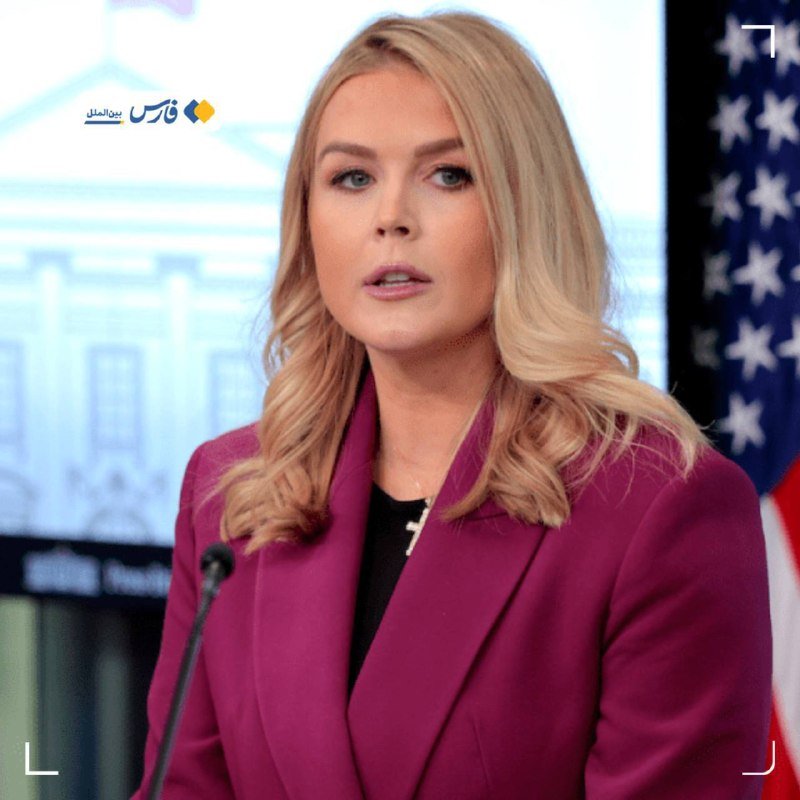 A blonde woman in a magenta blazer speaks at a podium in front of a White House backdrop and an American flag.