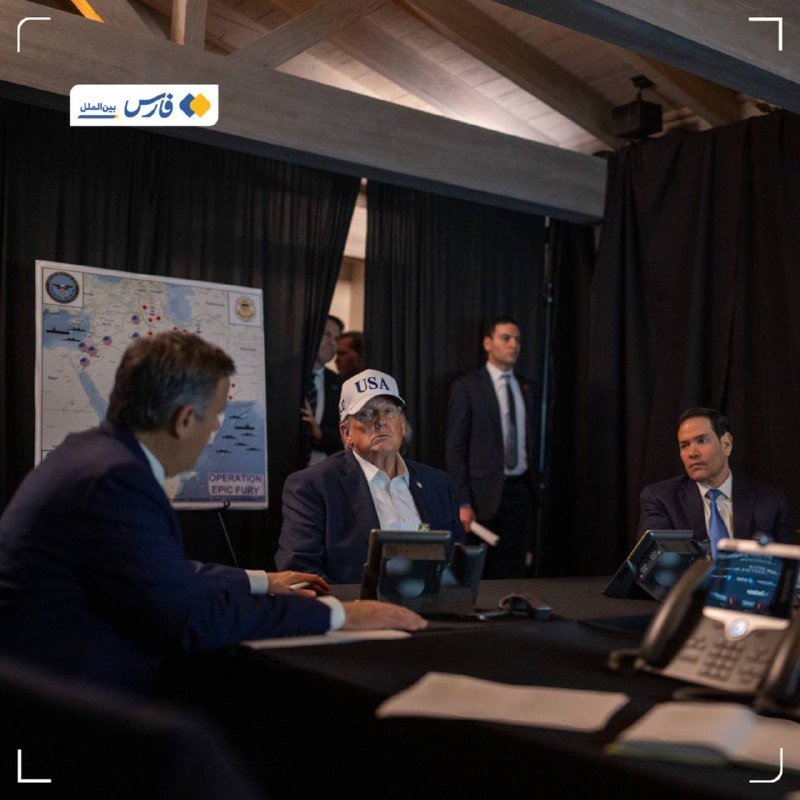 Three men in suits sit at a conference table with phones and documents, one wearing a "USA" cap, with a Middle East map labeled "OPERATION EPIC FURY" behind them.