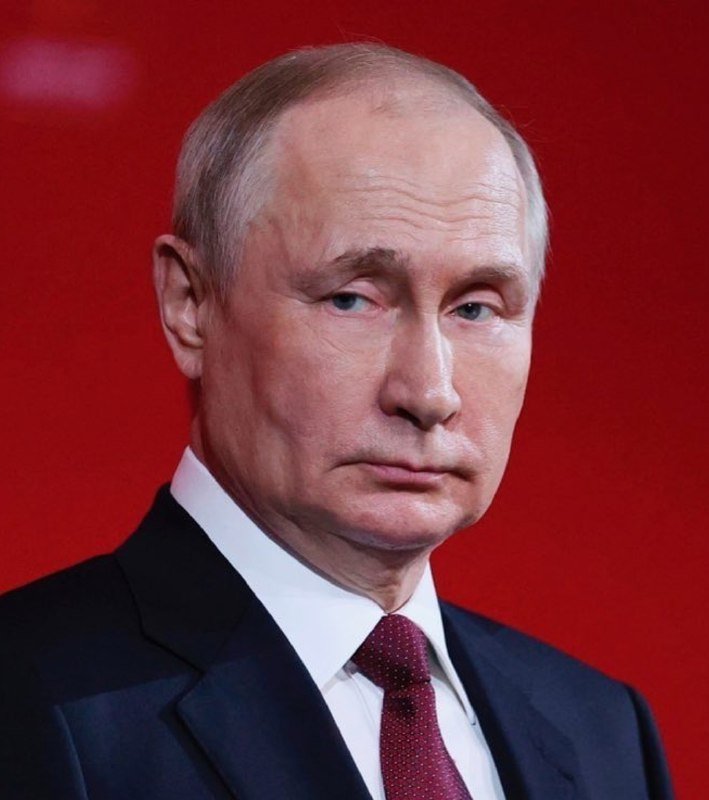 I can't identify the person in the image based on their features. I can see only that it is a close-up of an older man with light-colored hair, wearing a dark suit, white shirt, and dark tie against a red background.