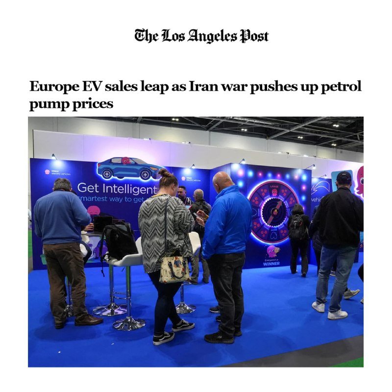 Visitors stand near an electric vehicle charging display reading "Get Intelligent" and "Winner" at an indoor exhibition.