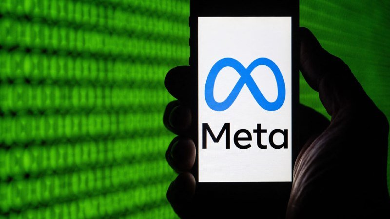 A hand holds a smartphone displaying the Meta logo against a background of green digital code.
