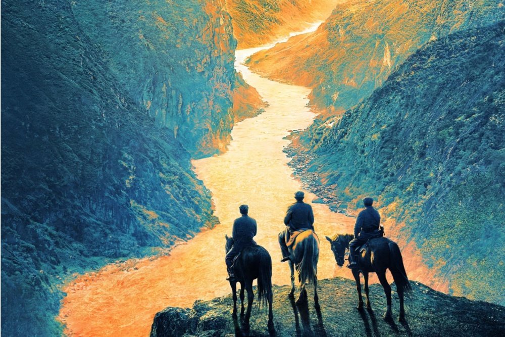Three horseback riders sit on a rocky outcrop overlooking a river winding through a steep, colorful canyon.