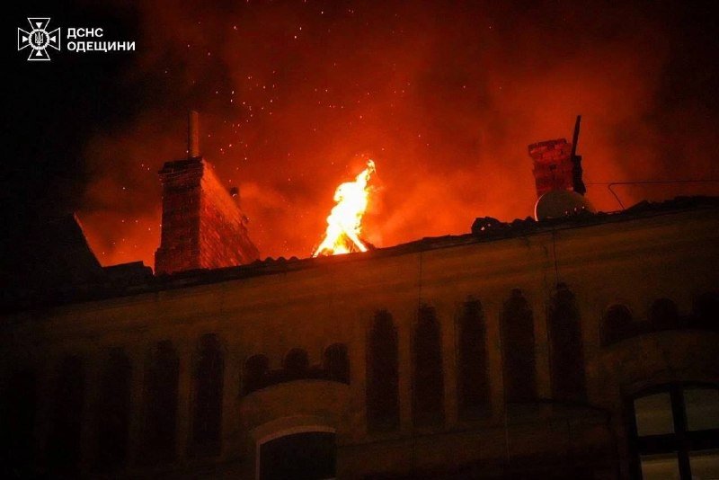 Flames and thick smoke rise from the roof of a multi-story building at night, with a logo reading "ДСНС ОДЕЩИНИ" in the upper left corner.
