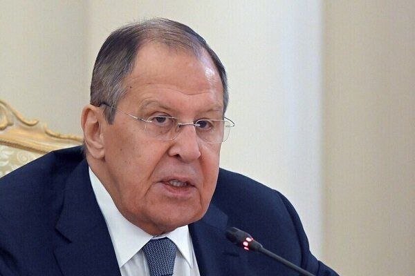 An older man in a dark suit, white shirt, and tie speaks into a microphone during what appears to be a formal meeting.