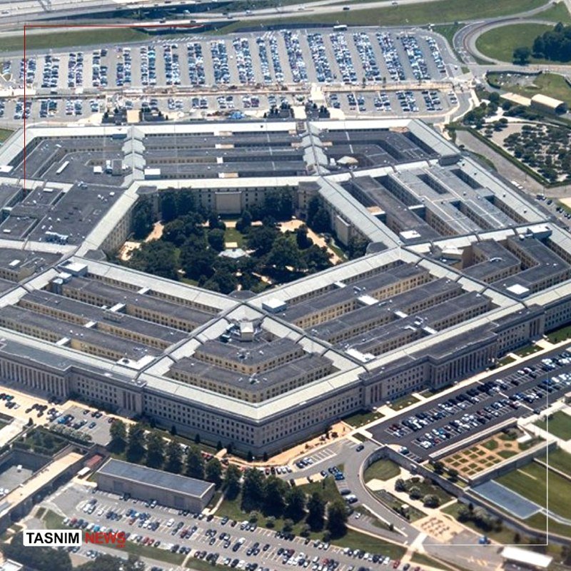 Aerial view of a large pentagonal building complex with a central courtyard, surrounded by parking lots filled with cars and adjacent roadways.