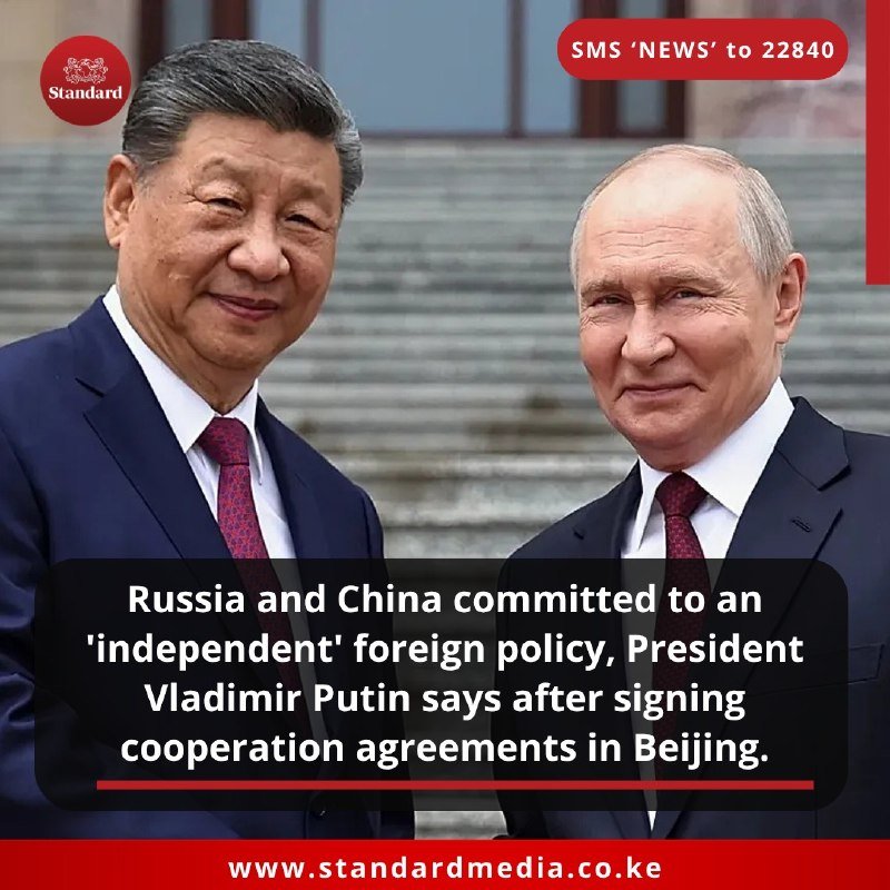 Two men in dark suits and red ties stand side by side in front of a stone staircase, smiling, with overlaid news text referencing Russia-China cooperation agreements in Beijing.