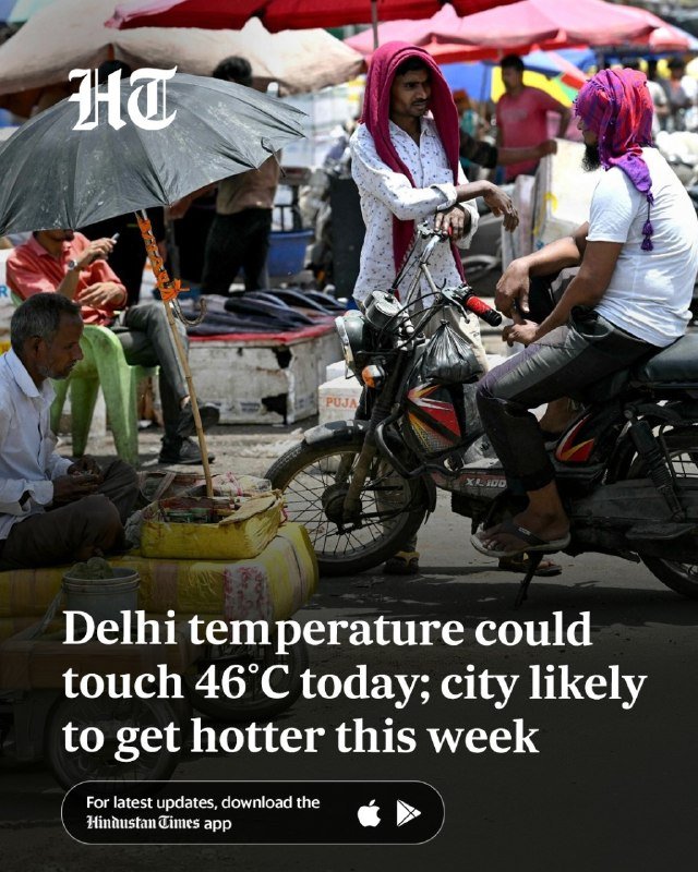 A man with a red cloth draped over his head sits on a motorcycle in a crowded outdoor market shaded by umbrellas.