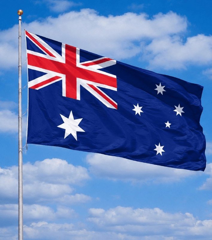 The Australian flag waves from a silver flagpole against a blue sky with scattered white clouds.