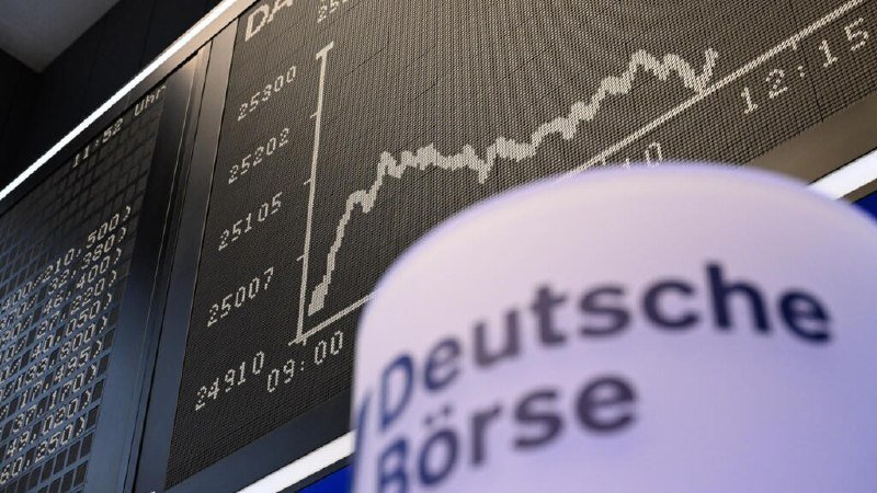 A digital display shows a rising line graph with numerical values, alongside a partially visible sign reading "Deutsche Börse" in the foreground.