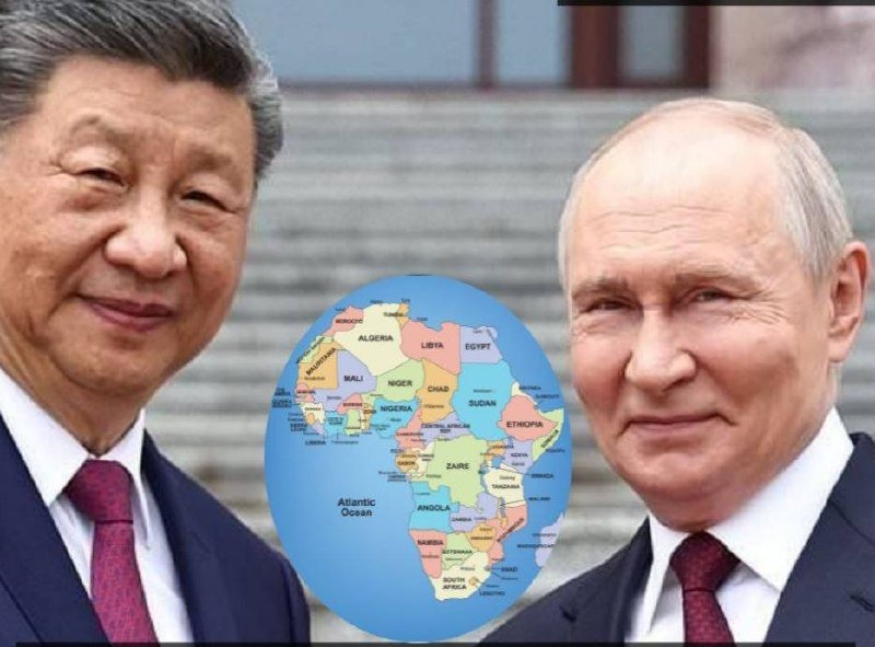Two men in dark suits and ties flank a colorful map of Africa centered between them against a stone-stepped background.