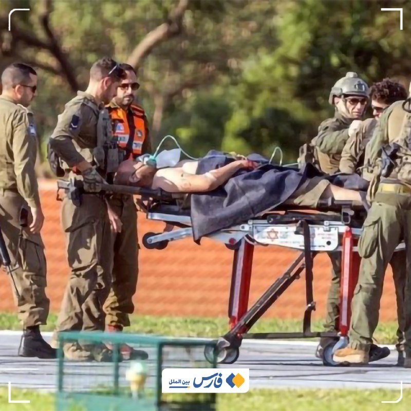 Uniformed personnel and a medic transport a shirtless person on an oxygen mask along a stretcher on a paved path.