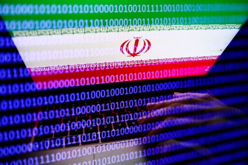 Hands type on a keyboard overlaid with binary code and the Iranian flag.