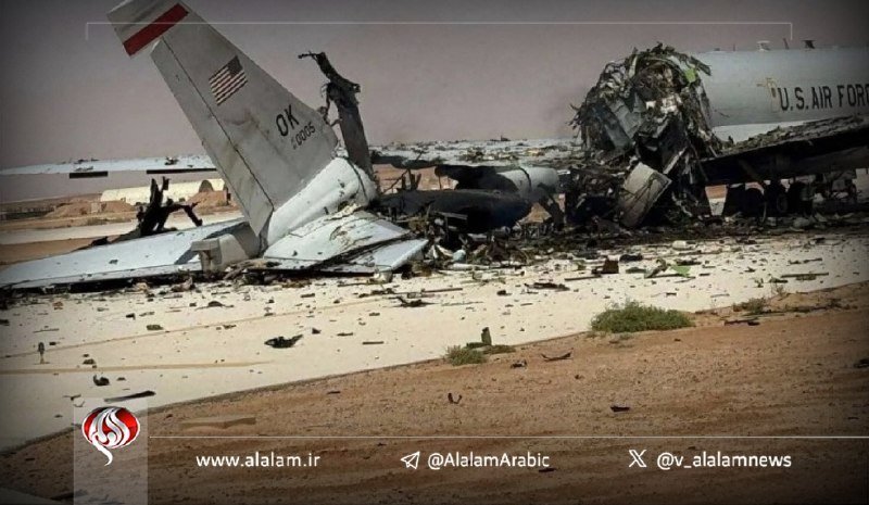 A destroyed "U.S. AIR FORCE" aircraft lies in pieces on a sandy surface, with its tail section and wreckage visible amid scattered debris.