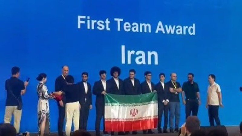 A team holding an Iranian flag stands on stage beneath a blue screen displaying "First Team Award Iran."