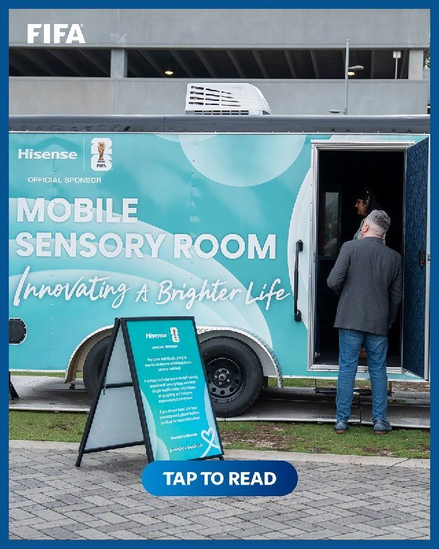 A teal trailer labeled "Mobile Sensory Room" with Hisense and FIFA branding stands outside as a man in a gray jacket enters through the open door.
