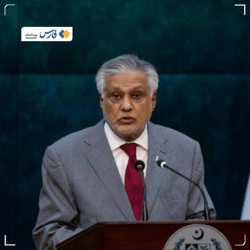 A grey-haired man in a grey suit and red tie speaks at a podium bearing an emblem with a crescent and star, set against a green marble backdrop.