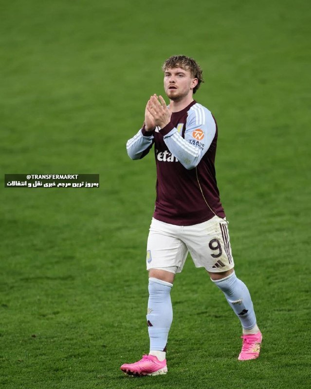 A soccer player in a claret and blue jersey with the number 9 stands on a green pitch, clapping his hands together.