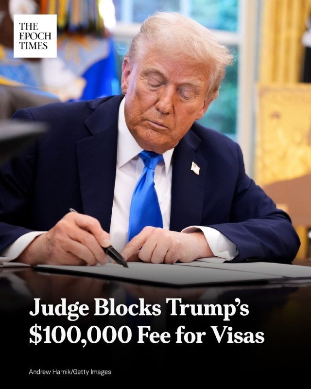 A man in a dark suit and blue tie signs a document at a desk, with the text "Judge Blocks Trump's $100,000 Fee for Visas" overlaid below.