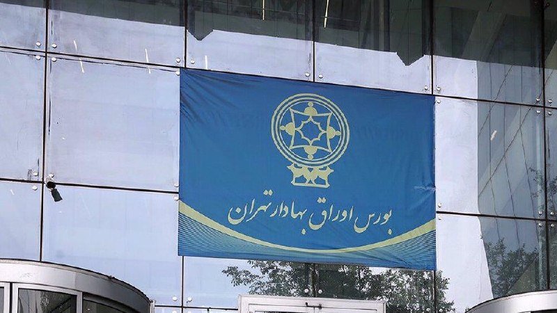 A blue banner displaying a yellow emblem and Persian script hangs on the glass facade of a modern building.