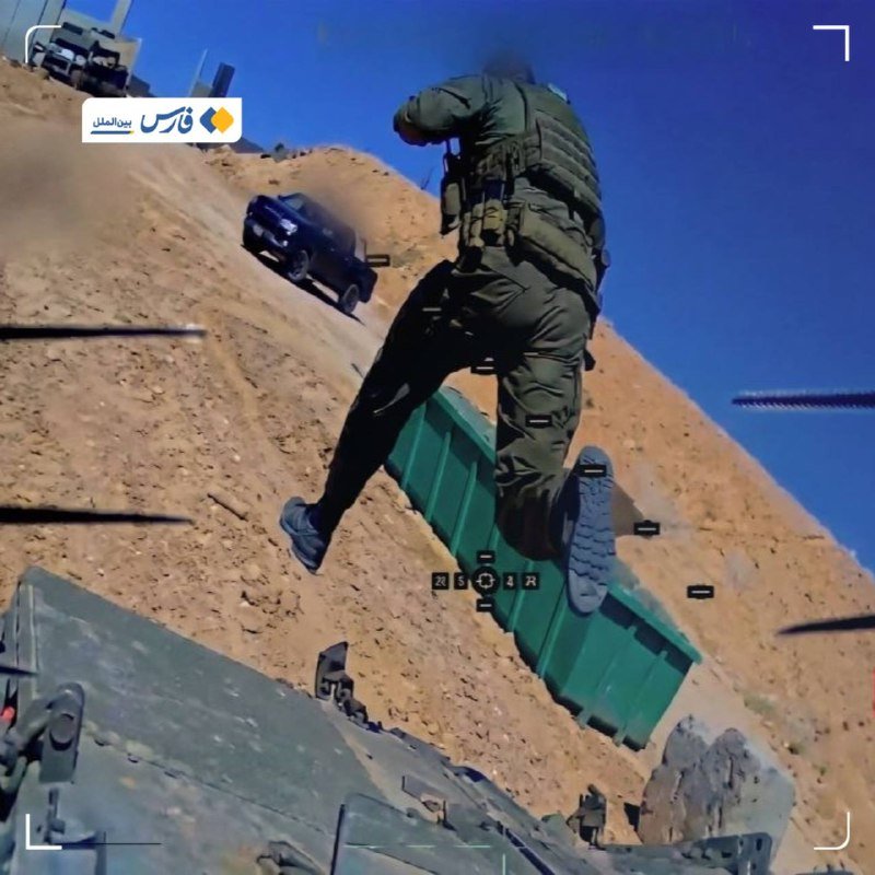 An armed soldier in tactical gear leaps onto a green container in a desert landscape, with a pickup truck and military vehicle visible in the background.